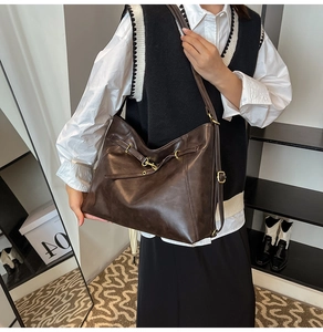 Detailed side view of vintage brown leather tote bag with gold buckle and adjustable strap