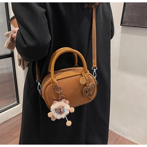 Close-up of brown Boston bag with plush lamb pendant on black wool coat for women