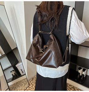 Dark brown convertible tote bag shown as a backpack on a model in a modern interior