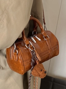 Brown bowling shoulder bag with plush dog charm and woven strap accessory