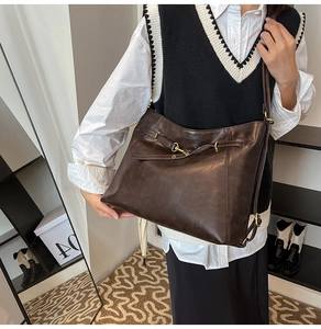 Detail view of large dark brown leather tote bag with vintage texture and metal hardware