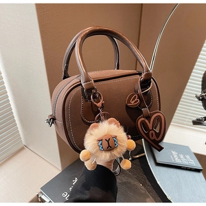Close-up of brown faux leather Boston bag with contrast stitching and plush charm decoration