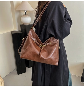Detail view of retro brown tote bag with matte leather texture and vintage gold buckle