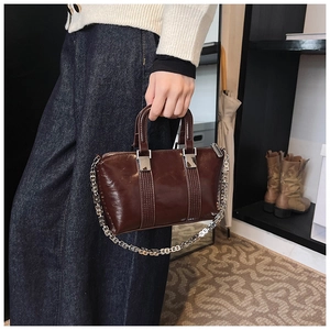 Detail of vintage brown oil-wax leather handbag with silver chain strap and vertical stitching