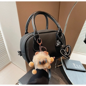 Detail of black Boston bag with contrast white stitching and cute bear charm accessories