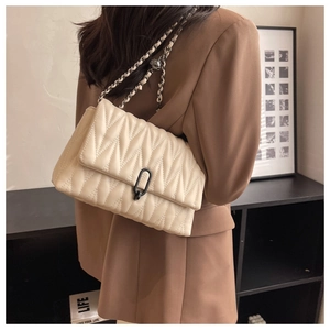 Detail of cream white quilted leather shoulder bag with chain strap and black geometric lock