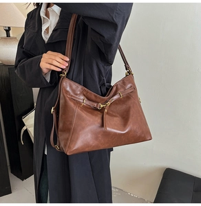 Detail of vintage brown leather tote showing long strap and antique gold buckle hardware