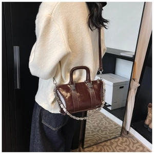 Detail view of brown vintage leather crossbody bag with silver G-chain and shoulder strap