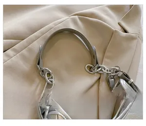 Détail du sac à bandoulière argenté avec poignée en cuir et chaîne en métal épais