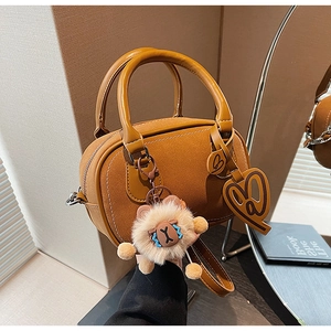 Detail of camel suede Boston bag featuring dual handles and cute sheep plush pendant