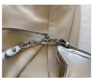 Détail du sac à main argenté avec une chaîne métallique et un crochet amovible chic