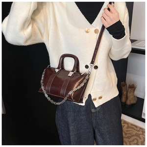 Detail of dark brown glossy leather crossbody bag with chain and vertical textured pattern