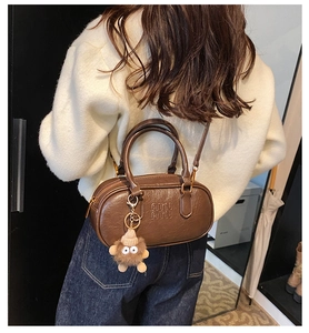 Détail du sac cylindre en cuir marron vintage avec gaufrage et charme en peluche