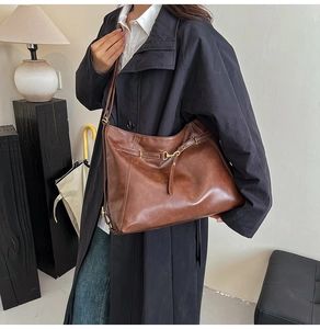 Close-up of the vintage brown faux leather texture and gold buckle detail on the tote bag