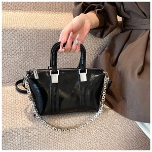 Detailed shot of a black patent leather handbag featuring a stylish silver G-link chain strap