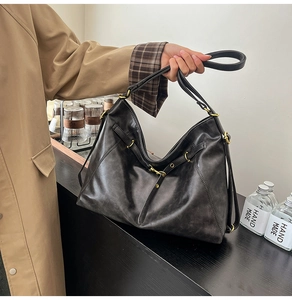 Detail of black leather tote bag showing vintage texture and brass hardware accents