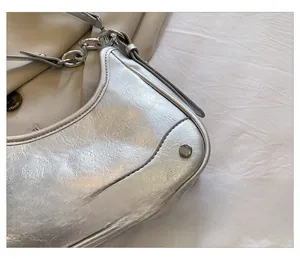 Gros plan du sac argenté avec texture en cuir craquelé et détails de chaîne métallique