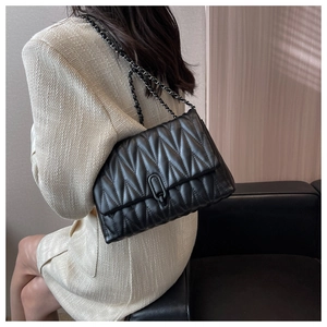 Detailed view of black quilted crossbody bag with stylish metallic chain strap and U-shaped lock