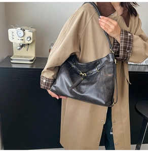 Close-up of minimalist black matte leather tote bag worn as a versatile shoulder bag