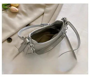 Détails du sac argenté montrant la doublure marron et la poche intérieure zippée