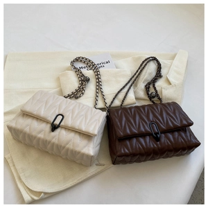 Close-up of quilted chain bags in beige and brown with elegant metallic sphere details
