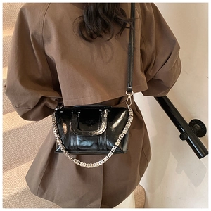 Close-up of black glossy leather bag with silver chain and dual straps for women