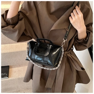 Detail of glossy black patent leather handbag with signature metal 4G chain and strap