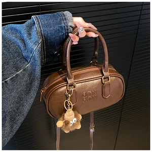 Détail d'un mini sac bowling en cuir marron vintage avec gaufrage ATN et breloque singe
