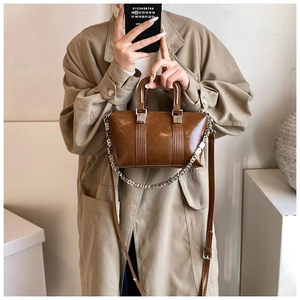 Detail of a brown glossy leather shoulder bag with silver square chain and dual straps