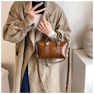 Detailed view of dark brown vintage oil-wax leather handbag with metallic chain detail