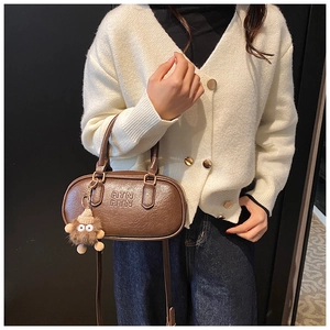 Détail d'un sac à main vintage en cuir marron avec lettres embossées et breloque peluche