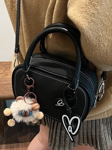 Chic black Boston bag with white stitching, plush sheep pendant, and heart charms on model