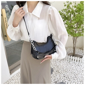 Détail du sac sous le bras noir en demi-lune avec chaîne argentée et rivets métalliques