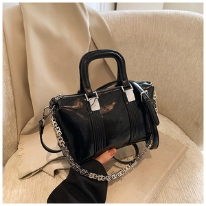 Close-up of black glossy patent leather Boston bag with silver chain and adjustable strap