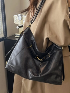Minimalist black oil wax leather tote bag shown with vintage trench coat for daily commuting