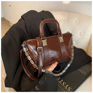 Close-up of brown leather bag featuring an elegant silver-tone designer chain strap
