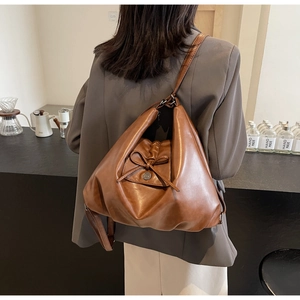 Detail view of brown soft leather tote bag with a bow accent and metal buckle design