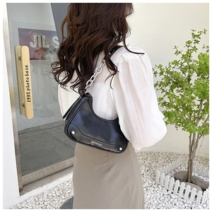 Détail du sac croissant noir brillant avec bandoulière chaîne argentée et logo