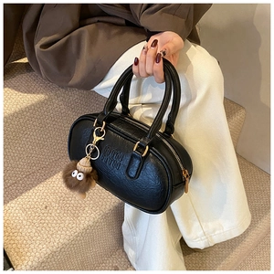 Détail du sac à main Boston noir avec gaufrage de marque et breloque en peluche
