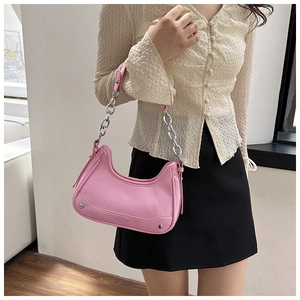 Détail d'un sac hobo rose en demi-lune avec chaîne argentée épaisse et logo gaufré