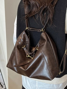 Minimalist large brown leather tote bag worn by a model in a casual versatile hobo style