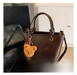 Dettaglio della borsa a secchiello in pelle vintage marrone scuro con orsetto