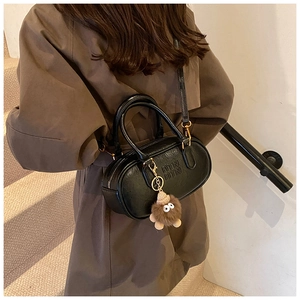Détail du sac à main ovale noir en cuir PU avec gaufrage ATN et breloque peluche monstre