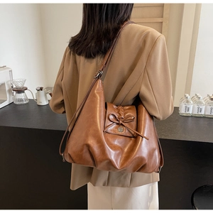 Detail view of brown leather Hobo bag with bow ornament and metal buckle detail
