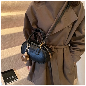 Détail du mini sac bowling vintage en cuir noir avec un porte-clé monstre en peluche mignon