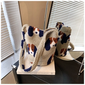 Close-up of fluffy lamb wool tote bag with cartoon dog patterns on an art book