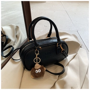 Détail du sac Boston en cuir PU noir avec logo ATN embossé et breloque en peluche douce