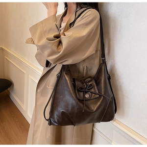 Detail of dark brown leather hobo bag featuring elegant bow tie and metal buckle