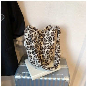 Detailed texture of a leopard print plush bucket bag placed on a silver suitcase