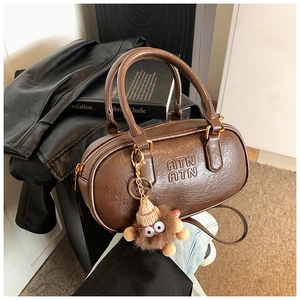 Détail du sac Boston en cuir marron vintage avec logo ATN et breloque monstre en peluche